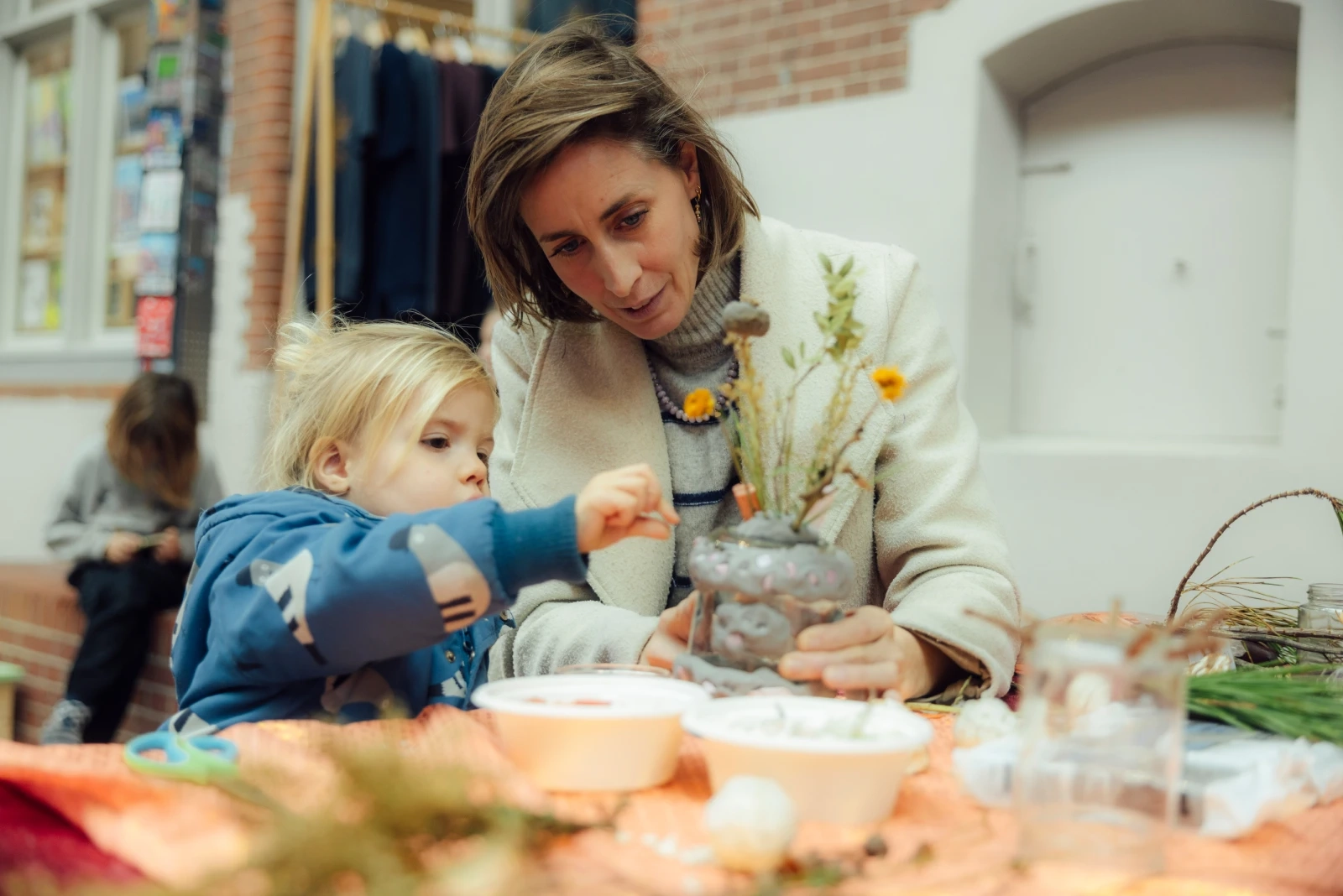 Moeder en kind knutselen samen met natuurlijke ingrediënten aan een creatieve workshop tafel