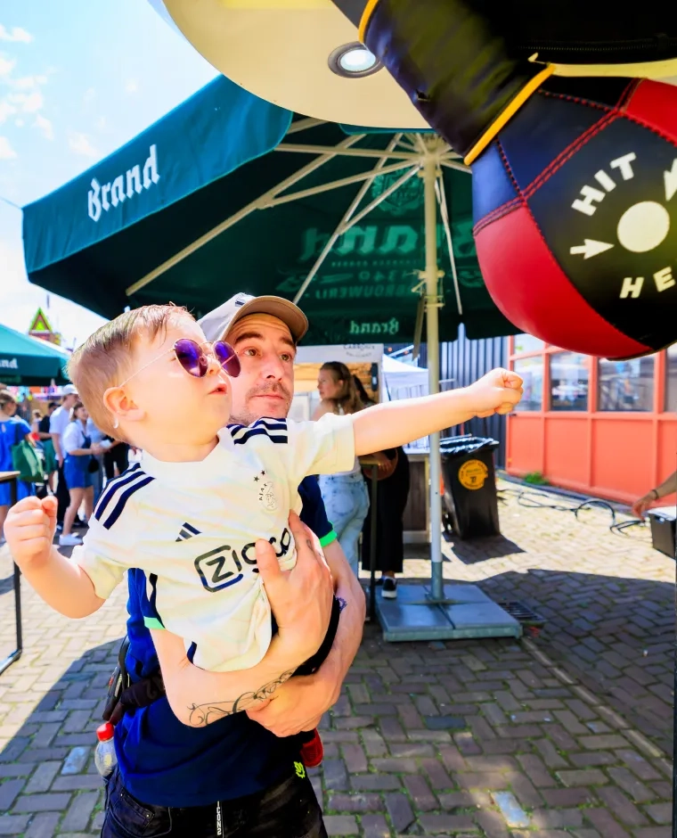 Een kind slaat speels tegen een boksbal op een festival.