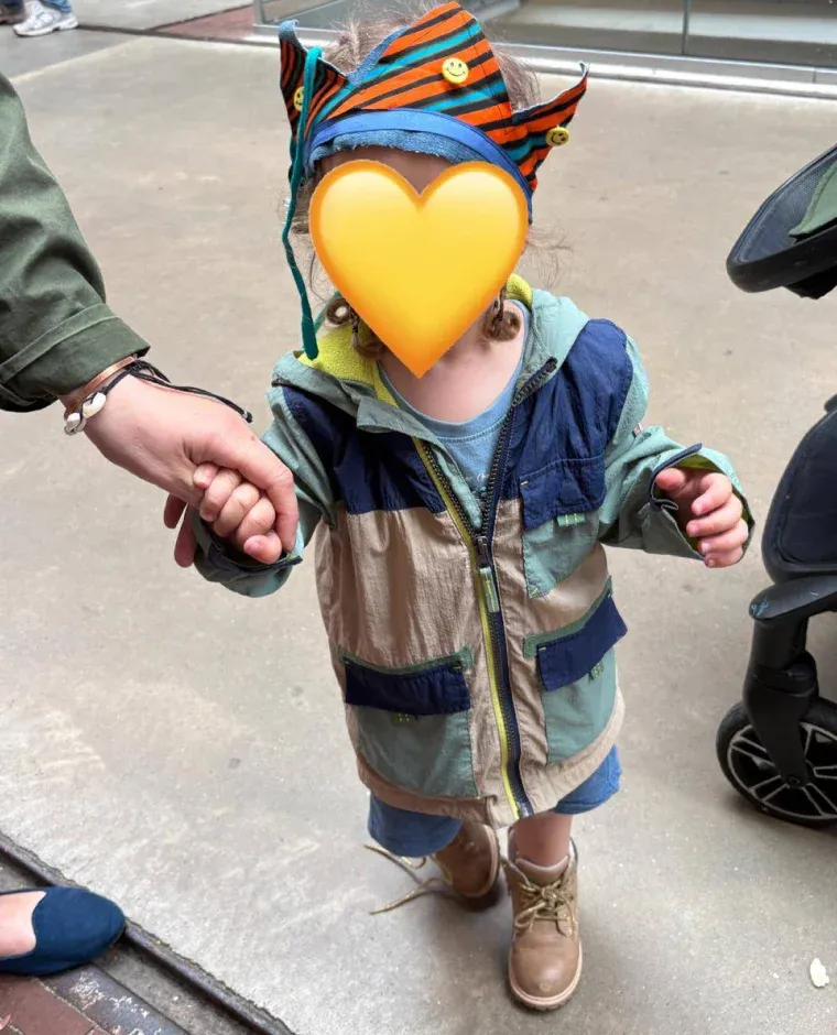 Peuter draagt een zelfgemaakte stoffen kroon met oranje en blauwe strepen