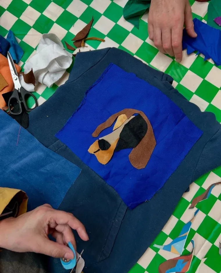 Handen bezig met het maken van een hondenkop van stof op denim