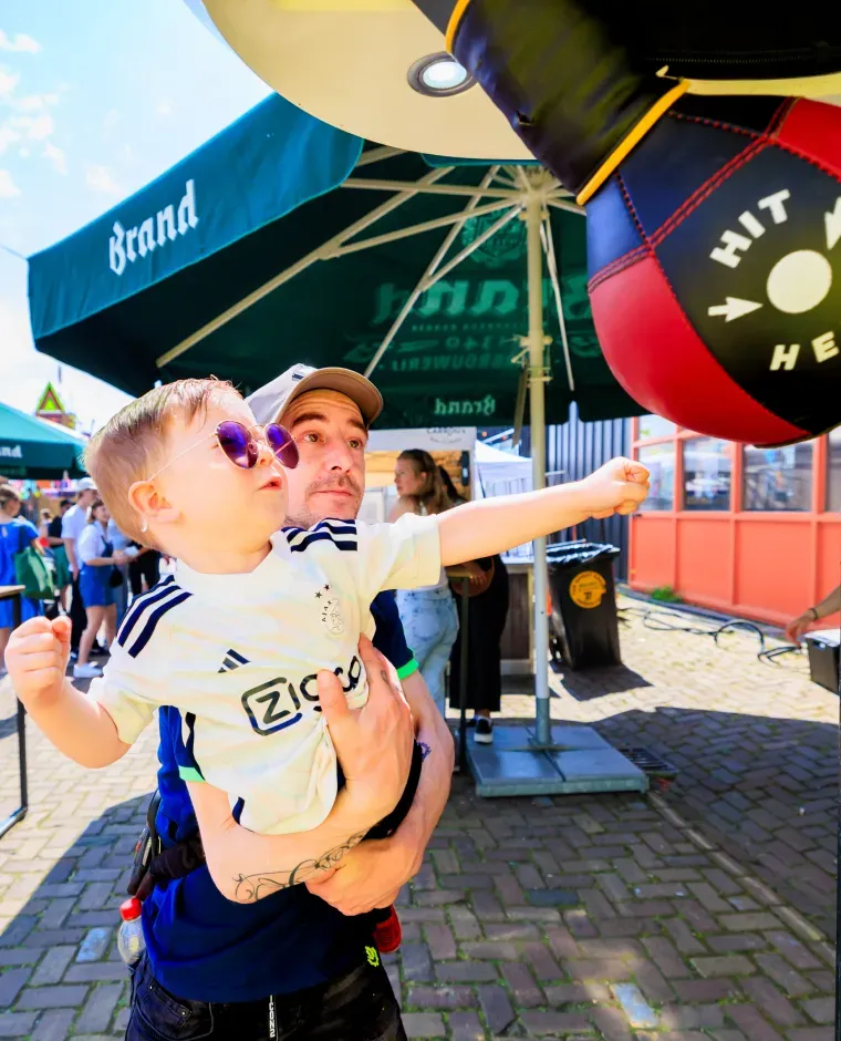Een kind slaat speels tegen een boksbal op een festival.