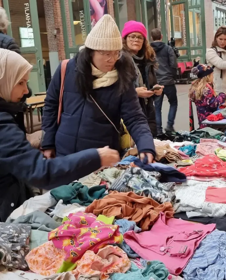 Vrouwen bekijken kleding op een evenemententafel