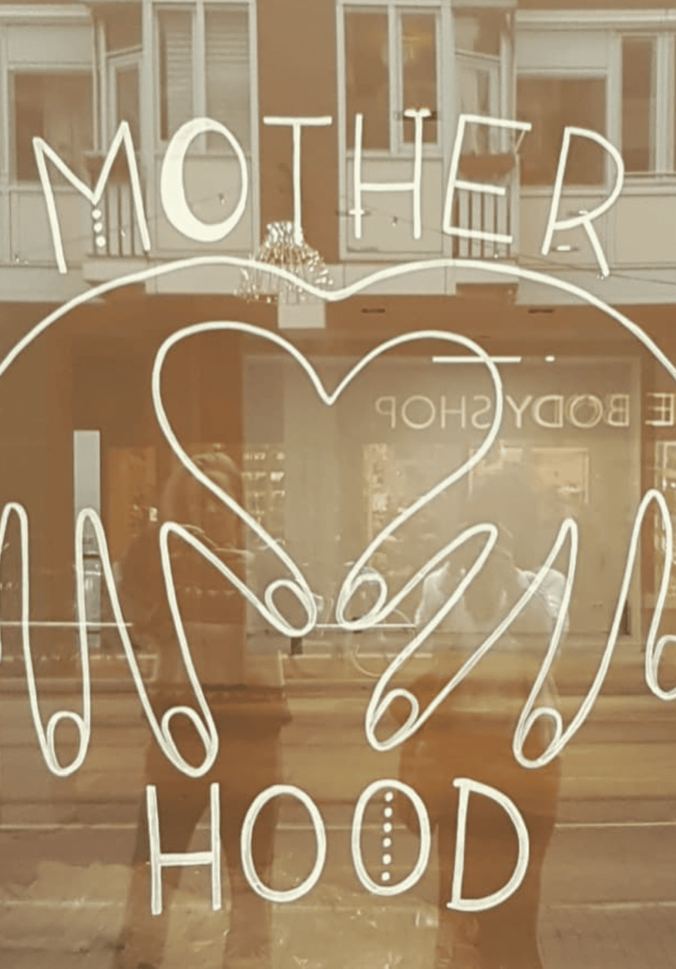 Motherhood logo on a window reflecting the team members